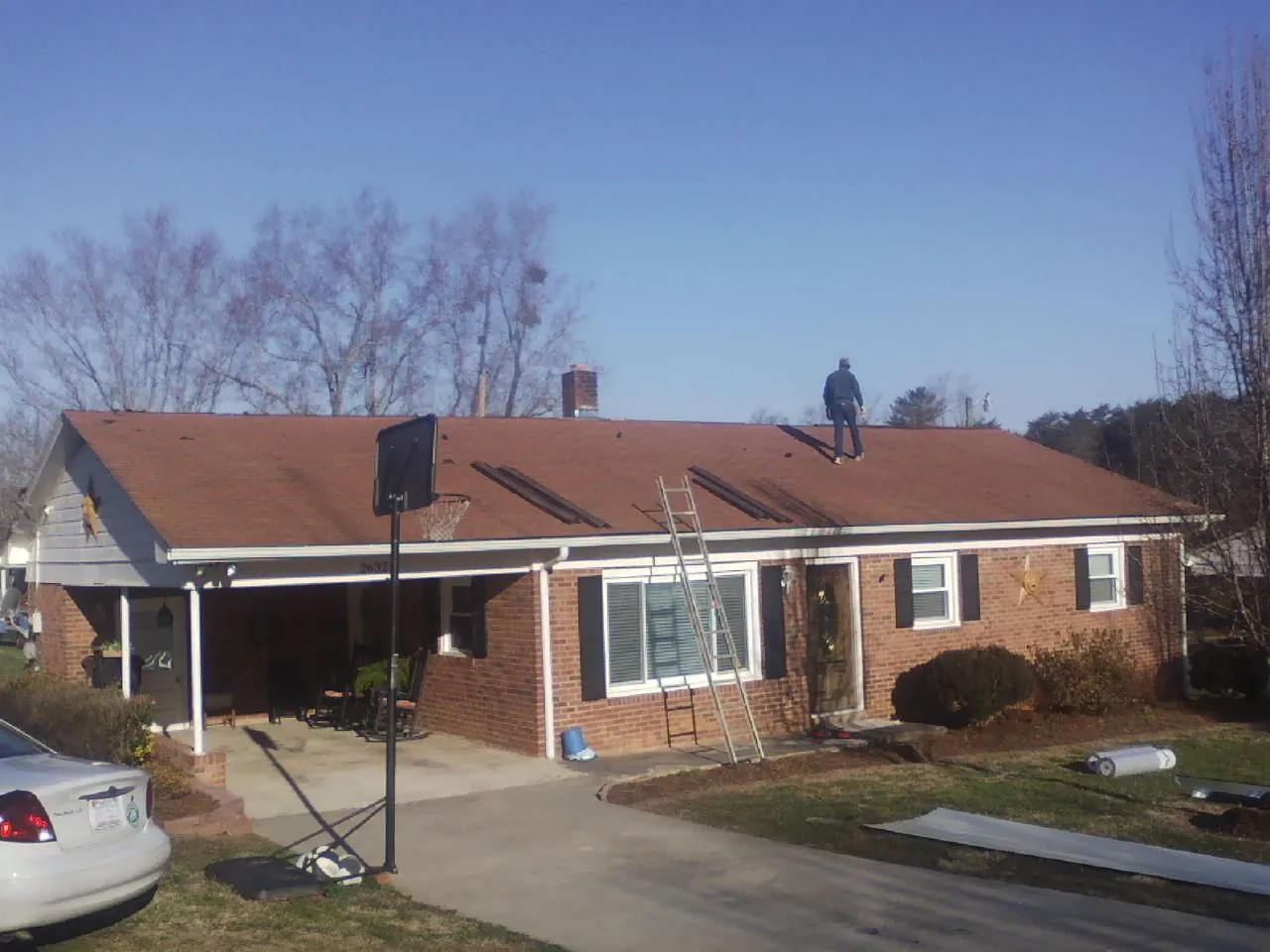 Roofer stripping a shingle roof on a brick ranch before metal panels in Van Buren