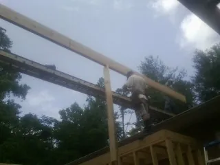 Carpenter setting a ridge beam over a new addition frame — Ice Dam Removal by Roofing Brothers in Van Buren