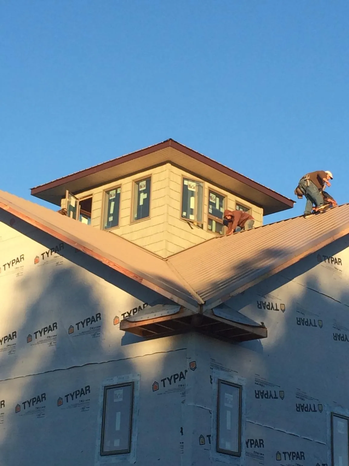 Roofers working around a rooftop cupola on a new metal roof at sunset — Roof Waterproofing in Van Buren by Roofing Brothers